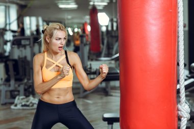 Atletik genç kadın kum torbası vasıl jimnastik salonu ile eğitim