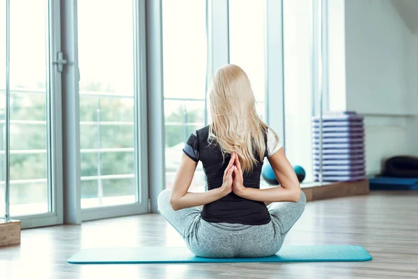 Young woman practicing yoga in gym. girl joining hands behind back — Stock Photo, Image