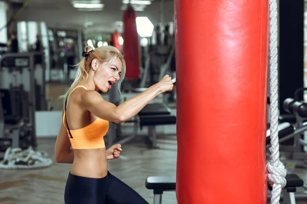 Atletisk ung kvinna utbildning med slagsäck på gym — Stockfoto