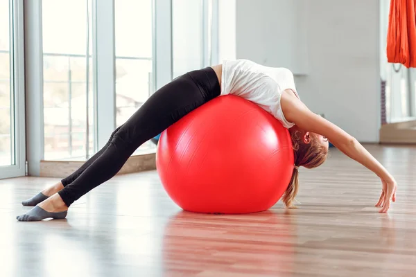 Jovem atlética fazendo exercícios com bola de fitness no ginásio — Fotografia de Stock