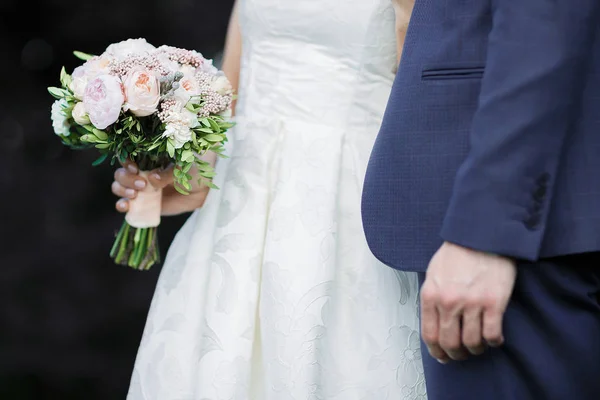 Bride and groom holding wedding bouquet — Stock Photo, Image