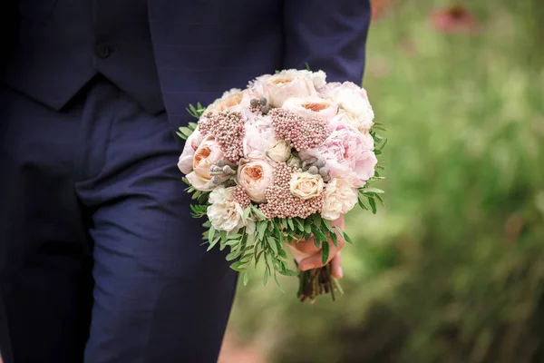 O noivo segurando um lindo buquê de casamento de peônias — Fotografia de Stock