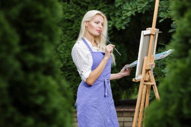 Tuval üzerinde kadın sanatçı onun elinde bir fırçayla çizer