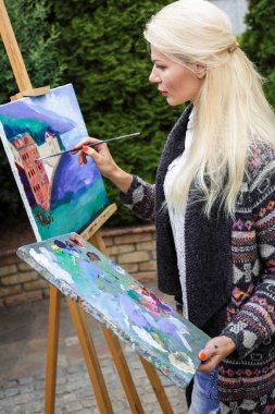 Tuval üzerinde kadın sanatçı onun elinde bir fırçayla çizer