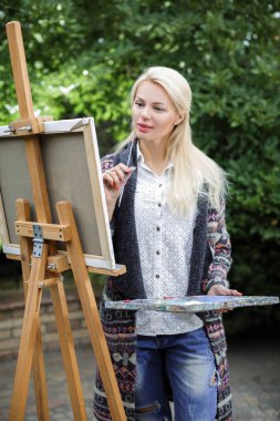 Tuval üzerinde kadın sanatçı onun elinde bir fırçayla çizer