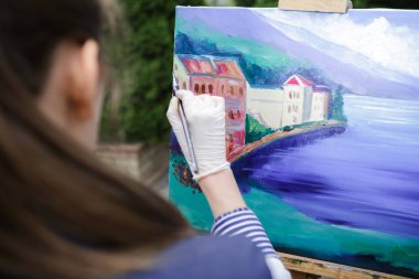 Tuval üzerinde kadın sanatçı onun elinde bir fırçayla çizer