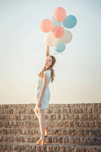 Красивая женщина с летящими разноцветными воздушными шарами — стоковое фото
