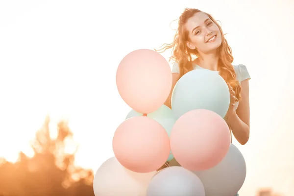 Vacker kvinna med flygande mångfärgade ballonger — Stockfoto