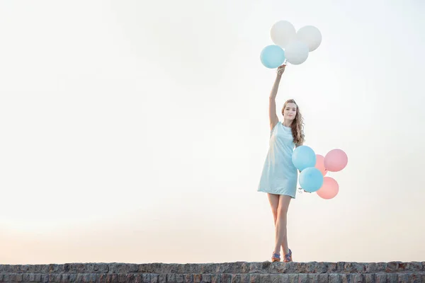 Hermosa mujer con vuelo multicolor globos — Foto de Stock