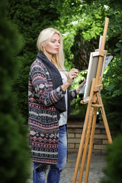 Žena umělec s kartáčem v ruce kreslí na plátně — Stock fotografie