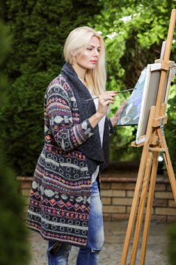 Tuval üzerinde kadın sanatçı onun elinde bir fırçayla çizer