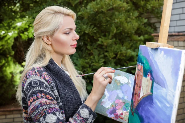 Mujer artista con un pincel en la mano dibuja sobre lienzo —  Fotos de Stock