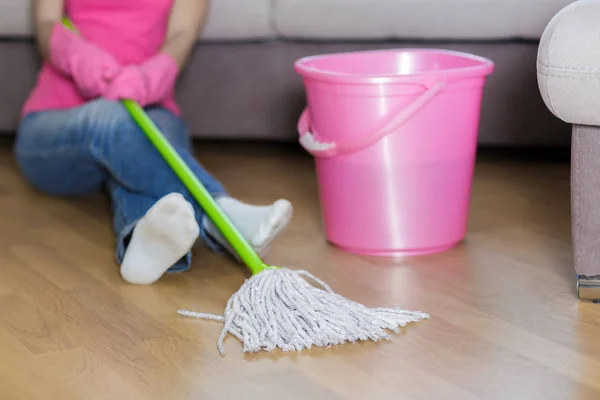 Tired woman in protective gloves is sitting near bucket. — Stock Photo, Image