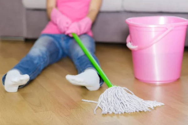 Moe vrouw in beschermende handschoenen zit in de buurt van emmer. — Stockfoto