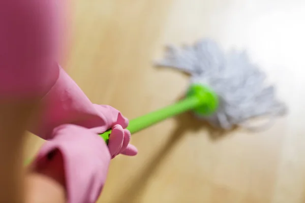 Vrouw in beschermende handschoenen met behulp van een NAT-mop tijdens het schoonmaken van de vloer — Stockfoto