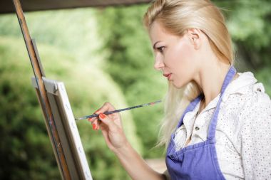 Tuval üzerinde kadın sanatçı onun elinde bir fırçayla çizer