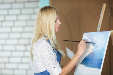 Tuval üzerinde kadın sanatçı onun elinde bir fırçayla çizer