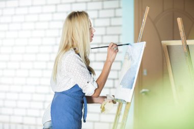 Tuval üzerinde kadın sanatçı onun elinde bir fırçayla çizer