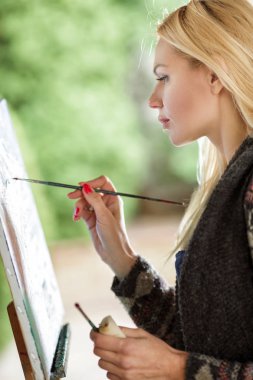 Tuval üzerinde kadın sanatçı onun elinde bir fırçayla çizer