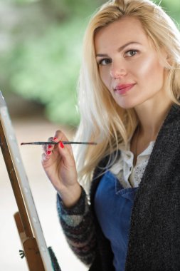 Tuval üzerinde kadın sanatçı onun elinde bir fırçayla çizer