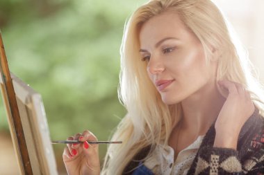 Tuval üzerinde kadın sanatçı onun elinde bir fırçayla çizer