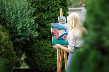 Tuval üzerinde kadın sanatçı onun elinde bir fırçayla çizer