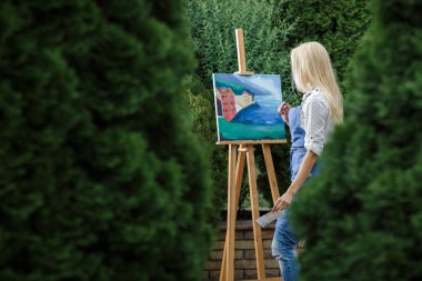 Tuval üzerinde kadın sanatçı onun elinde bir fırçayla çizer