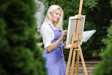 Tuval üzerinde kadın sanatçı onun elinde bir fırçayla çizer