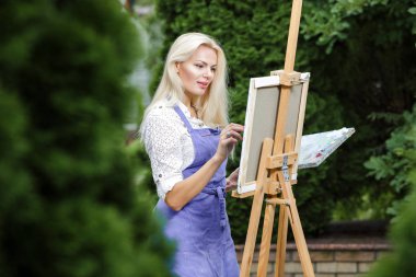 Tuval üzerinde kadın sanatçı onun elinde bir fırçayla çizer