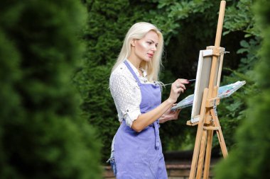 Tuval üzerinde kadın sanatçı onun elinde bir fırçayla çizer