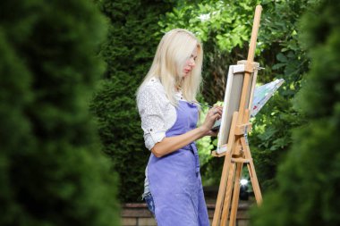 Tuval üzerinde kadın sanatçı onun elinde bir fırçayla çizer
