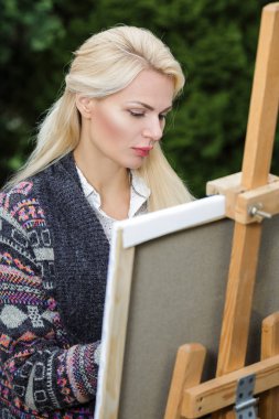 Tuval üzerinde kadın sanatçı onun elinde bir fırçayla çizer