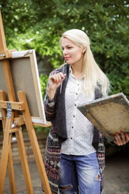 Tuval üzerinde kadın sanatçı onun elinde bir fırçayla çizer