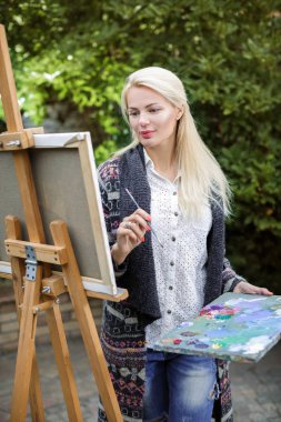 Tuval üzerinde kadın sanatçı onun elinde bir fırçayla çizer