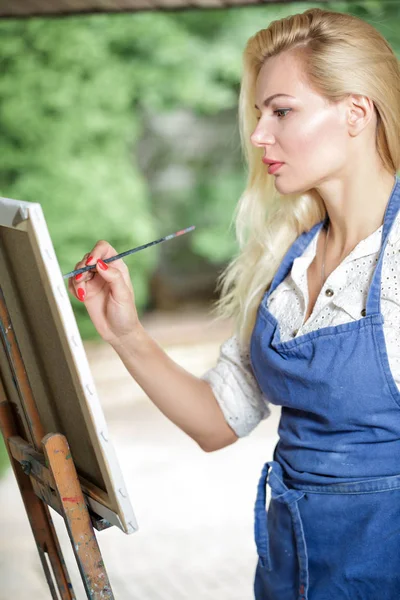 Tuval üzerinde kadın sanatçı onun elinde bir fırçayla çizer