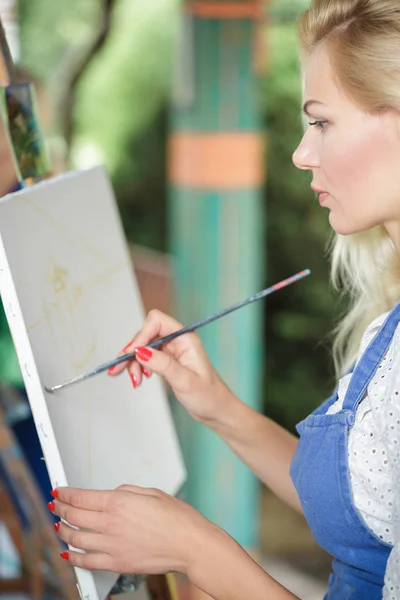 Жінка художник з пензлем у руці малює на полотні — стокове фото