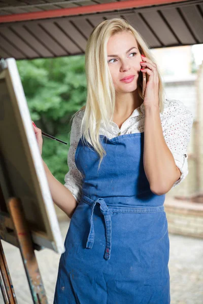 Žena umělec s kartáčem v ruce kreslí na plátně — Stock fotografie