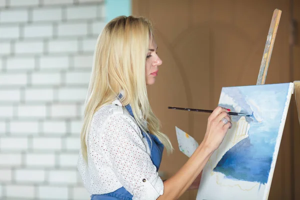 Mujer artista con un pincel en la mano dibuja sobre lienzo —  Fotos de Stock