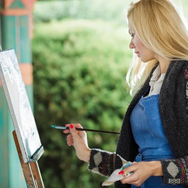 Mujer artista con un pincel en la mano dibuja sobre lienzo —  Fotos de Stock