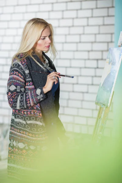 Artista mulher com um pincel na mão desenha sobre tela — Fotografia de Stock