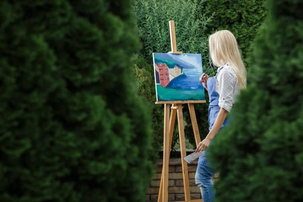 Tuval üzerinde kadın sanatçı onun elinde bir fırçayla çizer