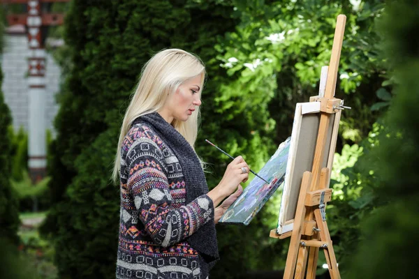 stock image woman artist with a brush in her hand draws on canvas