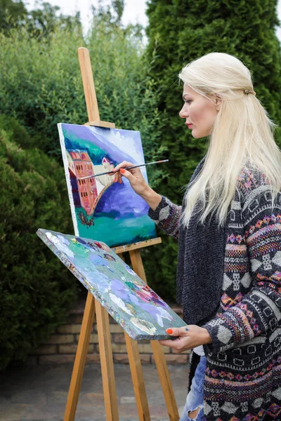 Mujer artista con un pincel en la mano dibuja sobre lienzo —  Fotos de Stock