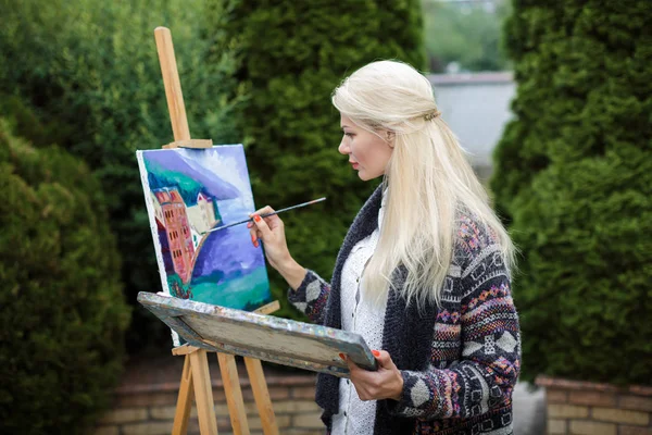 Tuval üzerinde kadın sanatçı onun elinde bir fırçayla çizer