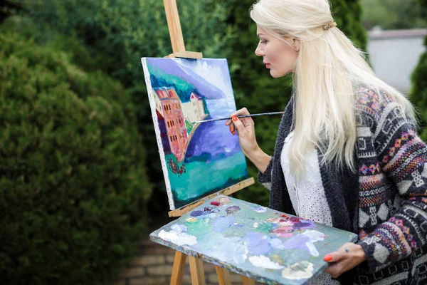 Tuval üzerinde kadın sanatçı onun elinde bir fırçayla çizer