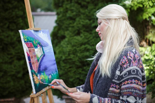 Woman artist with a brush in her hand draws on canvas — Stock Photo, Image