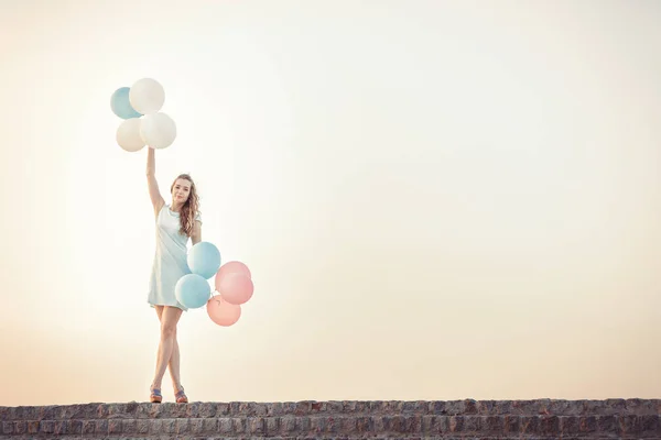 Schöne Frau mit fliegenden bunten Ballons — Stockfoto