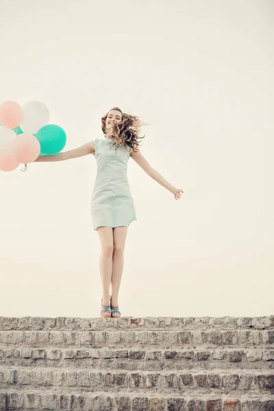 Красивая женщина с летящими разноцветными воздушными шарами — стоковое фото