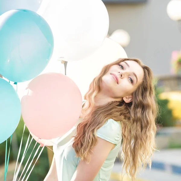 Beautiful woman with flying multicolored balloons — Stock Photo, Image