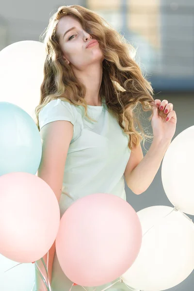 Beautiful woman with flying multicolored balloons — Stock Photo, Image